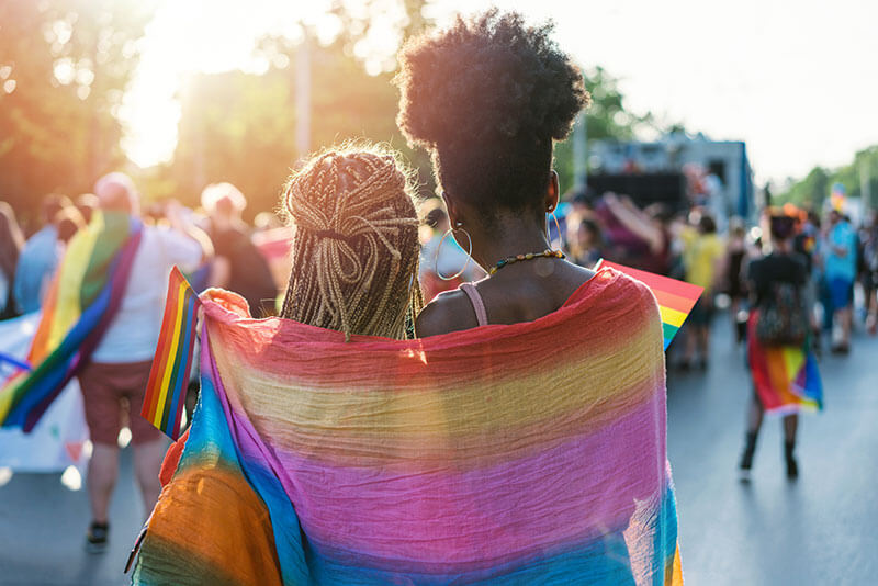 Two women wrapped in pride flag